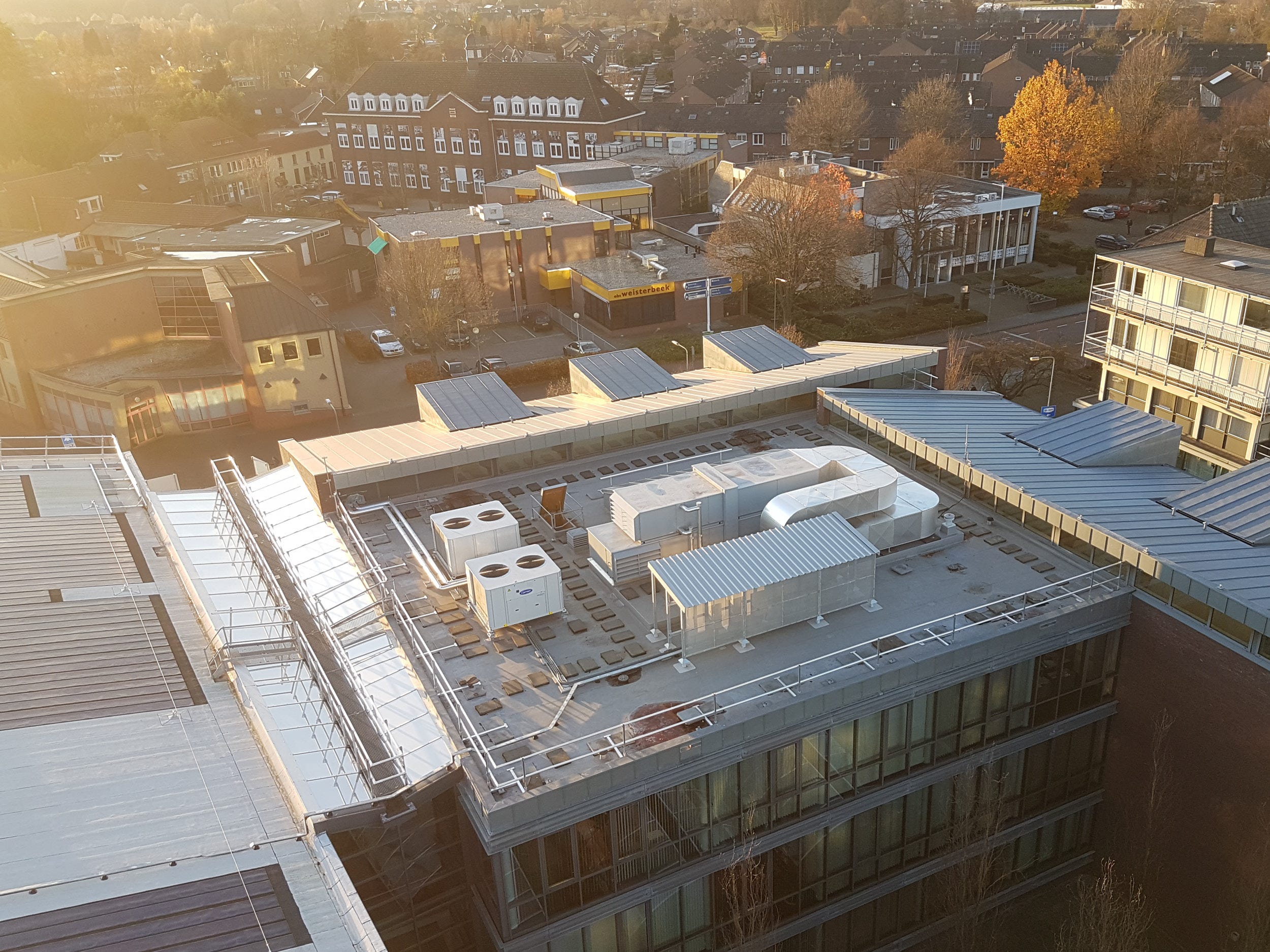 Afbeelding van een dakdekker die witte dakbedekking op een plat dak aanlegt